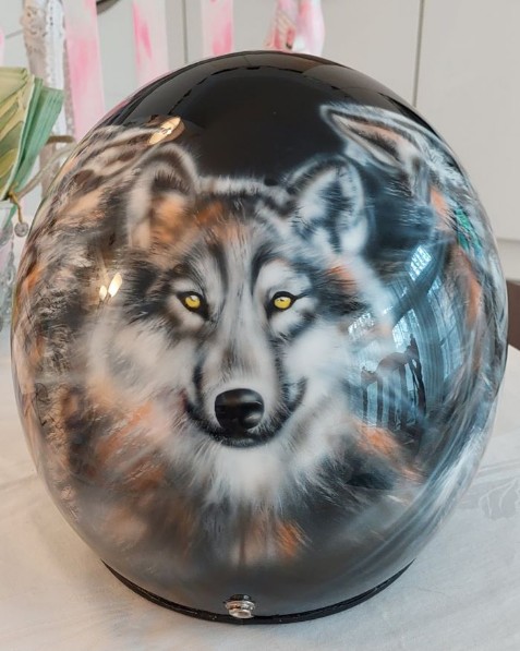 es wurde auf ein schwarzen Helm ein Wolfgesicht in schwarz weiss und leicht orange geairbrush die Augen sind in gelb